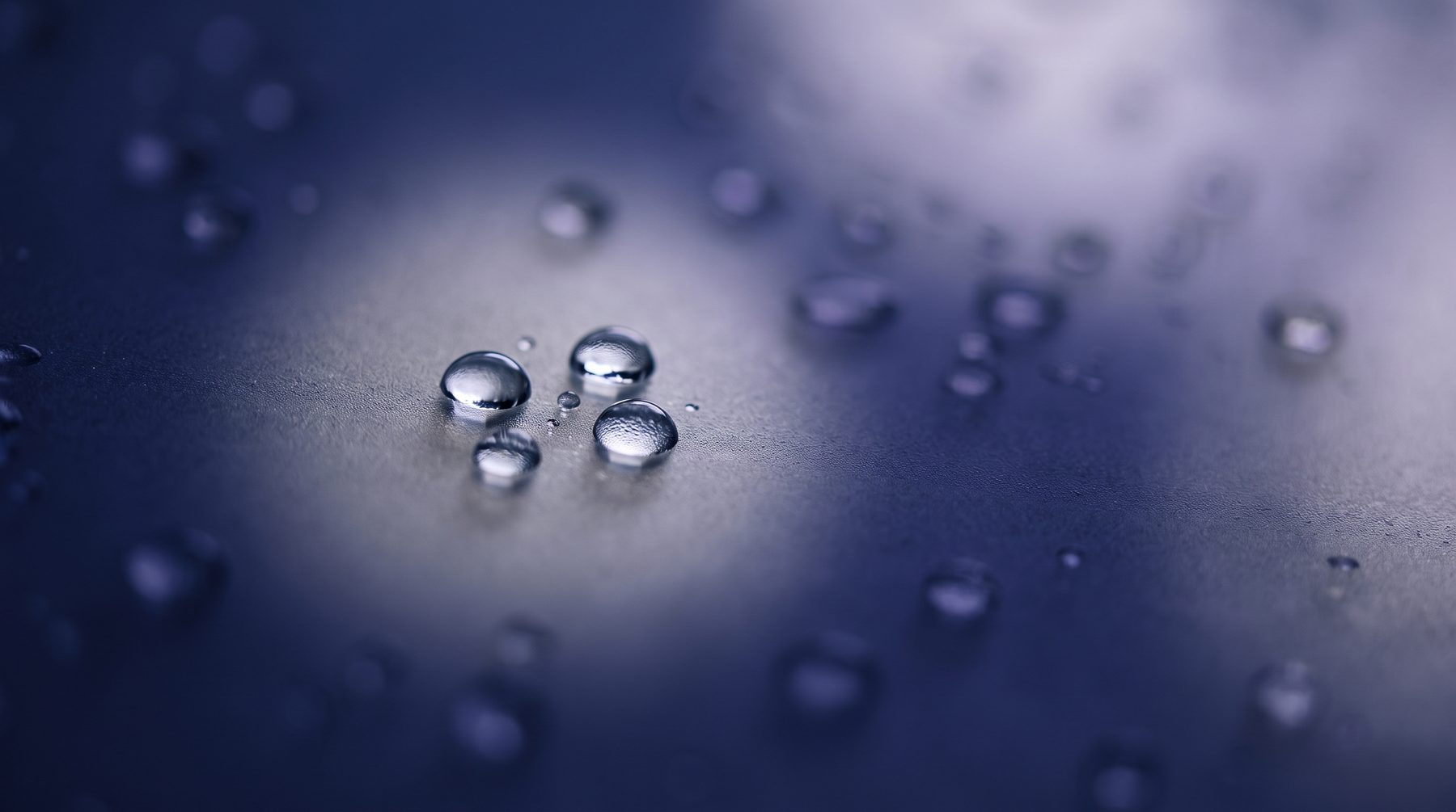 Water droplets on frosted glass, backlit in the brand's indigo tone