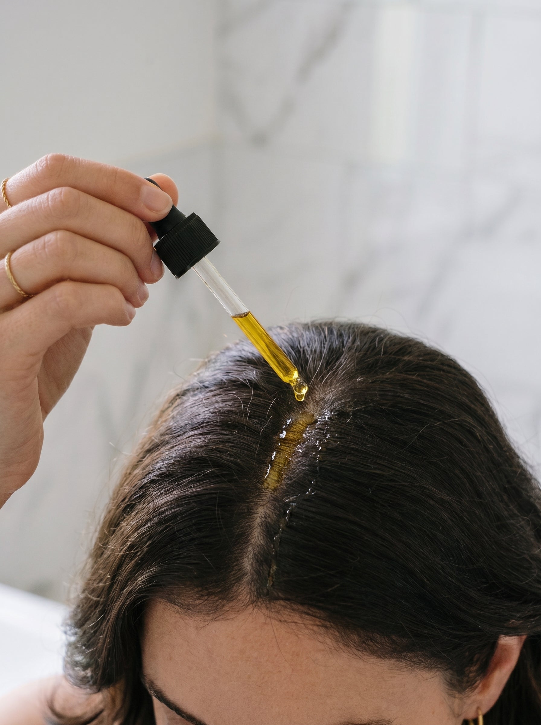 Applying Rosemary Scalp Strengthening Oil to the scalp with a dropper